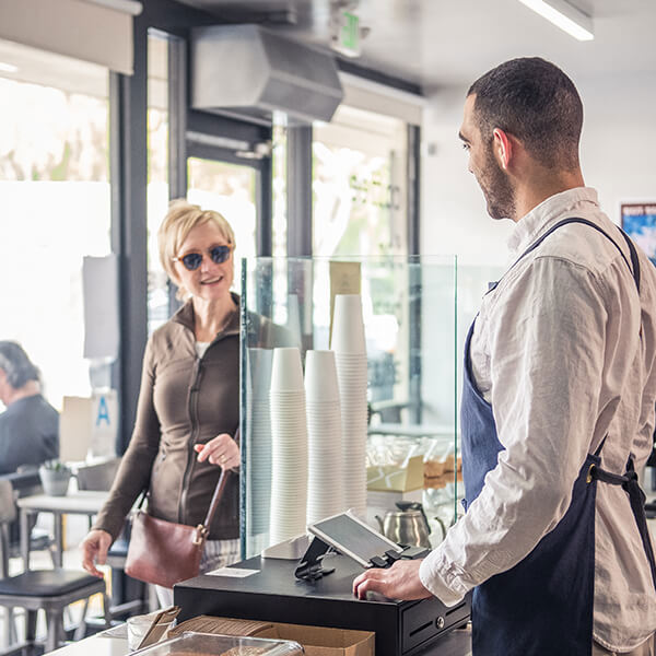 A barista greets a guest entering a coffee shop