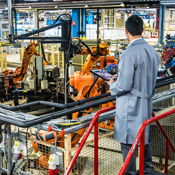 A technician stands in a warehouse overlooking machinery